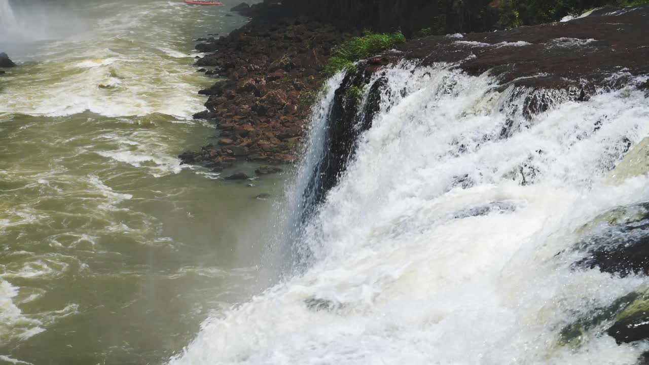 cerca de las cascadas de slo mo que se estrellan en la piscina de color, arroyo claro que cae del borde escarpado del acantilado, acantilado rocoso cubierto de río áspero que desemboca en el suelo rocoso en las cataratas de iguacu, argentina