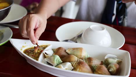 person savoring seafood dish with dipping sauce