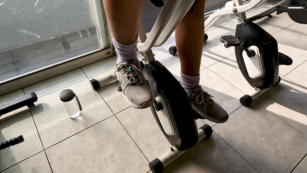 Close static shot of feet and legs of man on stationary bicycle