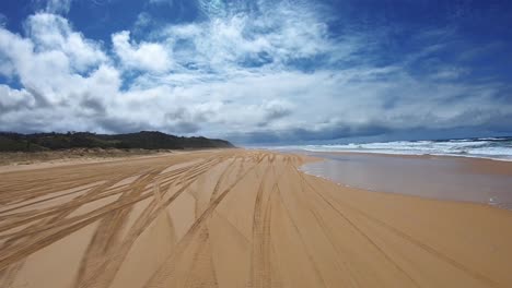 punto de vista de conducción mirando hacia atrás de una playa desierta de queensland con dunas bajas bajo un cielo azul con bancos de nubes blancas - ideal para el reemplazo de la pantalla verde de la escena interior del automóvil