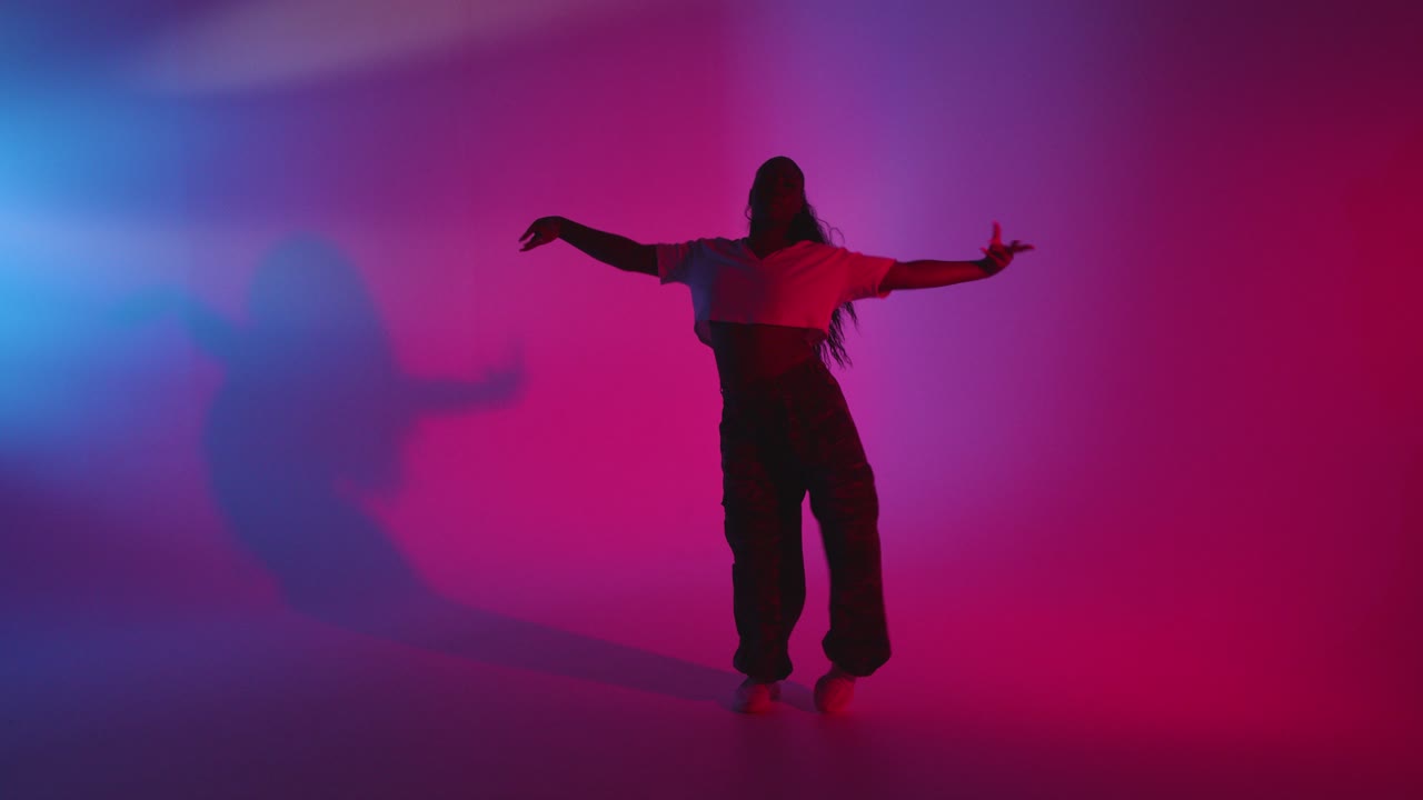 파란색과 분홍색으로 조명 된 배경 2 에 대해 춤추는 젊은 여성의 전체 길이 스튜디오  ⁇