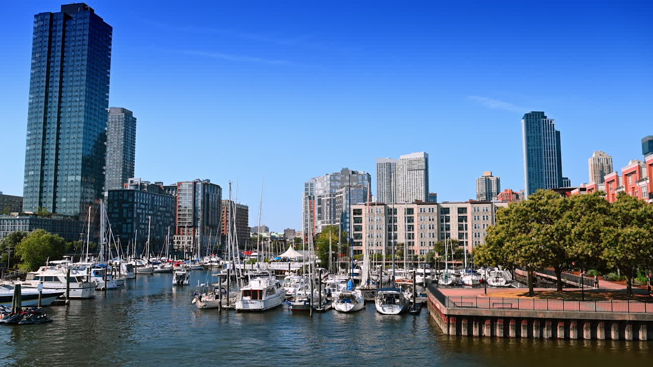 New Jersey, USA, 19 August 2025: Many boats and yachts stand on anchor at the berths in Jersey City, USA. Beautiful high-rise buildings at backdrop