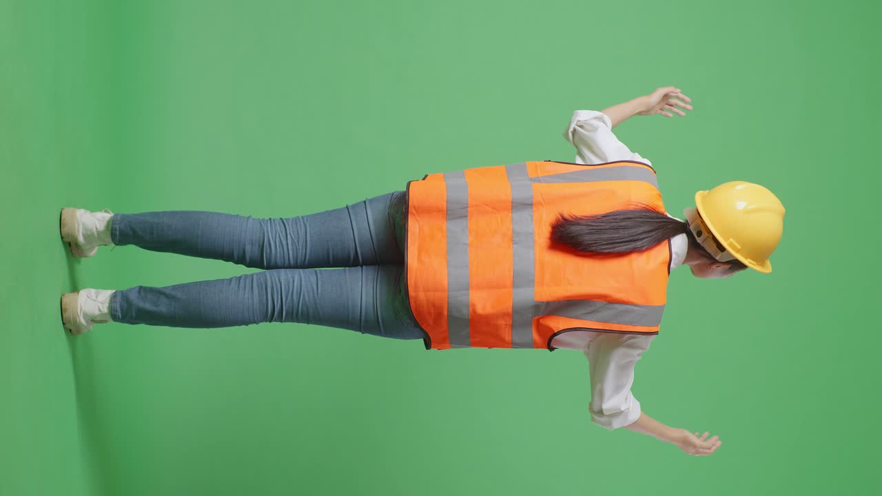 Full Body Back View Of A Female Engineer With Safety Helmet Spreading Arms While Standing In The Green Screen Background Studio