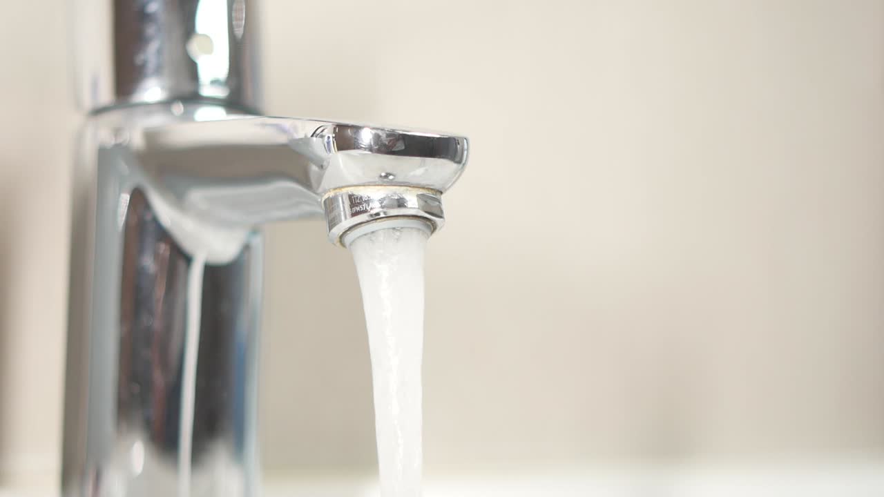 primer plano de un grifo de cromo con agua corriente