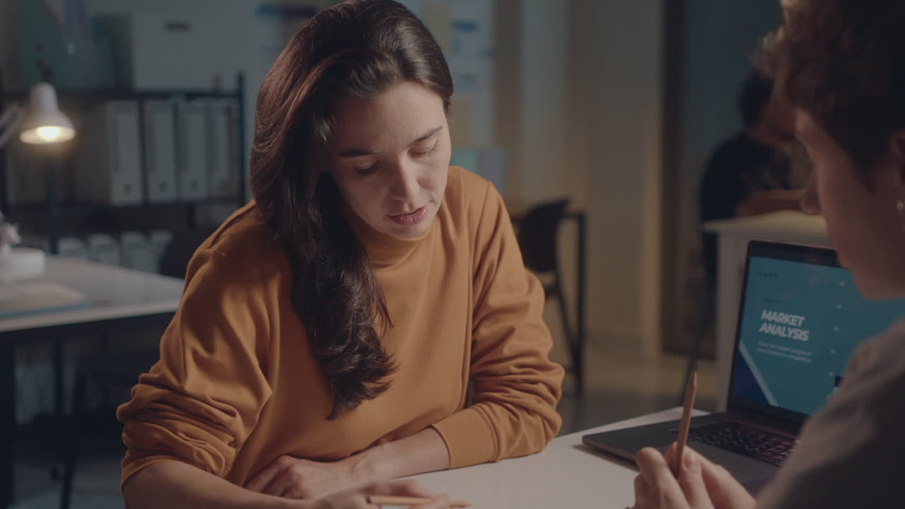 Woman Discussing Business Project with Female Colleague at Night