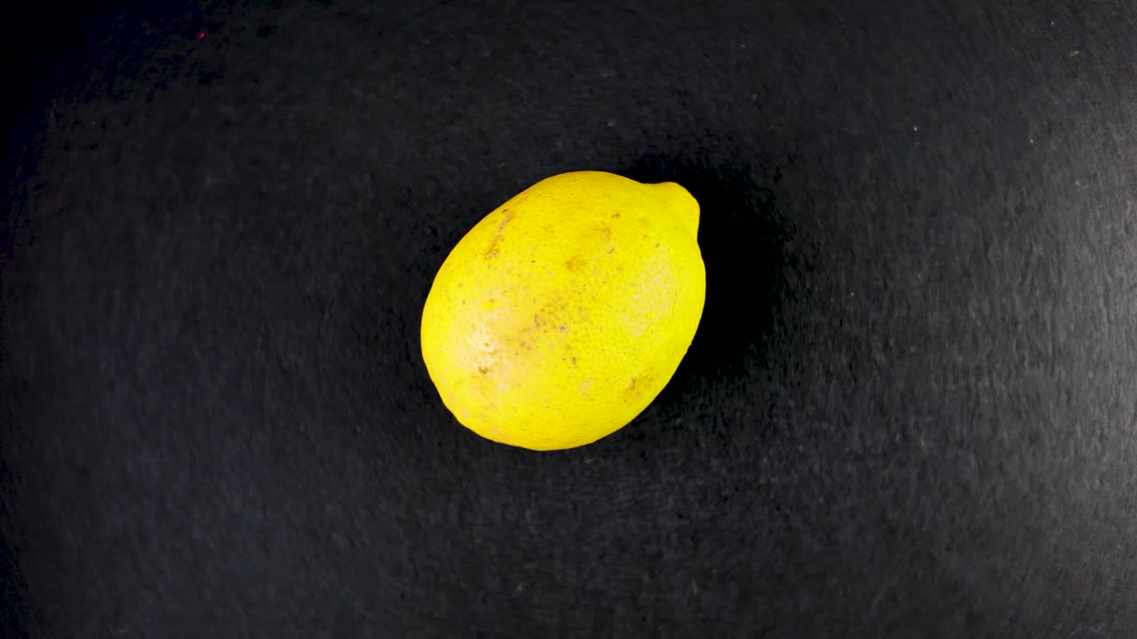 A vibrant yellow lemon captured against a stark black background emphasizing its freshness.