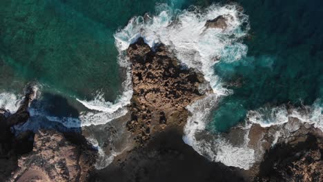 top-down lowering over ocean waves crashing on rocky coast near porto dos frades, madeira