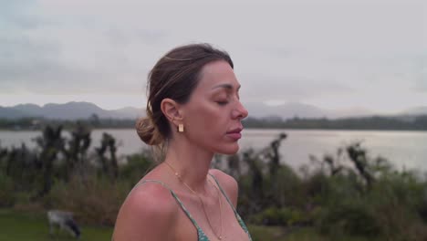 close up of meditating girl with closed eyes - lakeside outdoor yoga