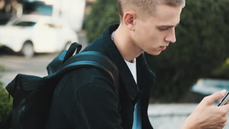 young student using mobile phone outdoors.