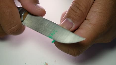 Footage-of-hands-slowly-sharpening-a-pencil-and-some-coloured-pencils-with-a-sharp-knife