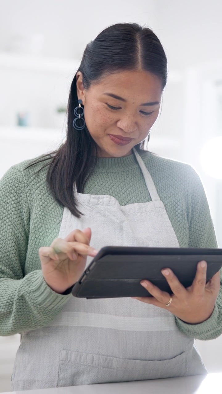 Young Woman Wearing Apron Using Digital Tablet in Kitchen