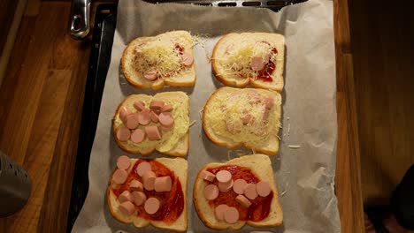 agregando queso rallado encima de sándwiches caseros estilo estudiante para cocinar en horno caliente