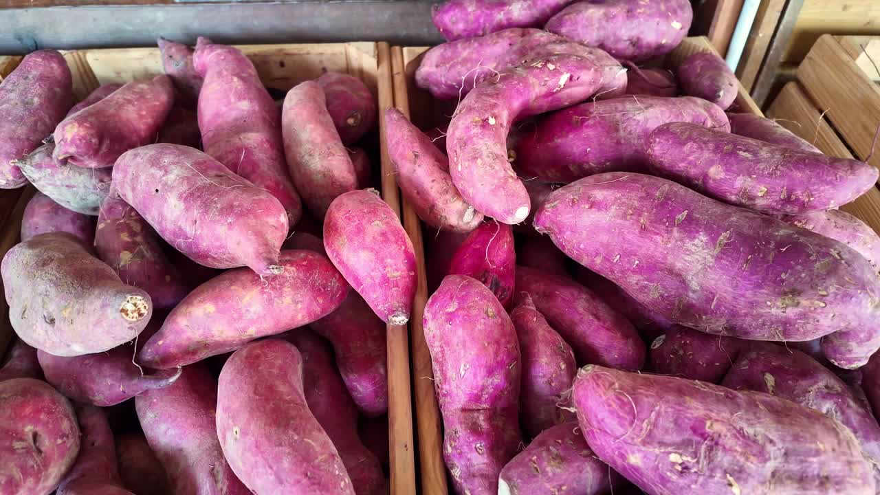 Static close-up shot of sweet potatoes with reddish skin arranged in wooden crates, showing natural textures and organic shapes