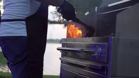 mexican latin barbecue griller preparing charcoal on grid fire for steak raw meat at sunset garden lake party flames