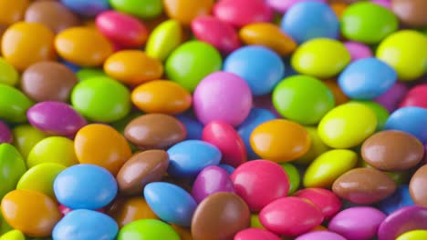 slow motion close-up of round colorful chocolate candies, dragee. rotation and fall multicolored chocolate candies