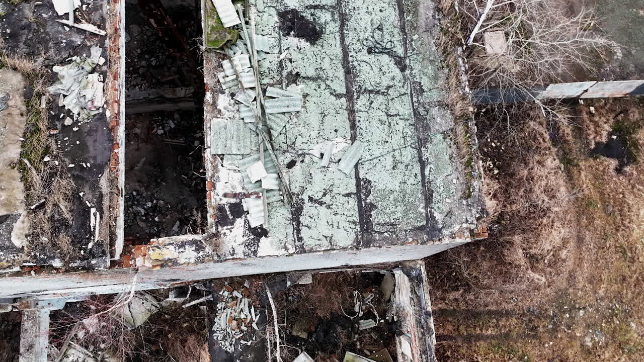 Remnants of the damaged factory building. Destroyed industrial premises overgrown with trees. Aerial view.