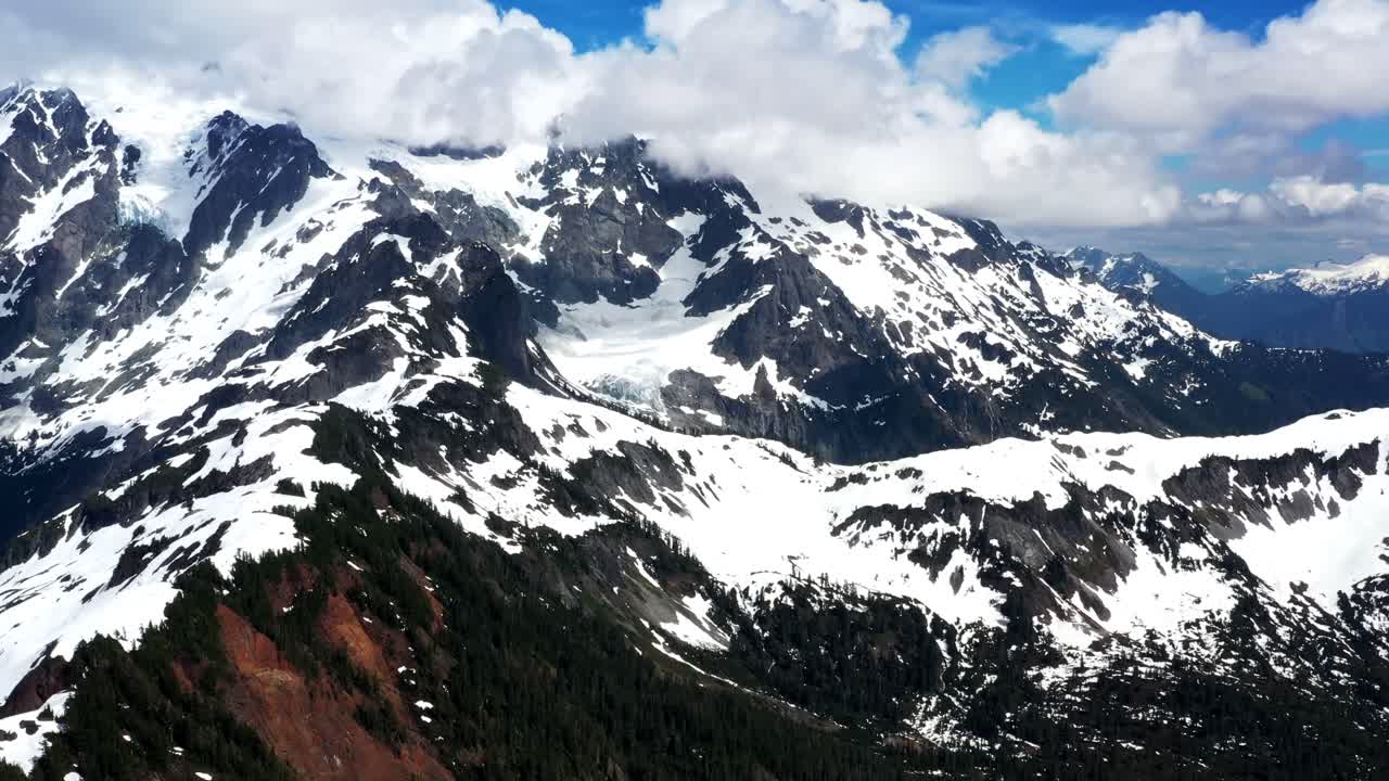High aerial view of mountain range and landscape covered in snow on a cloudy day in Washington State, Pacific Northwest.