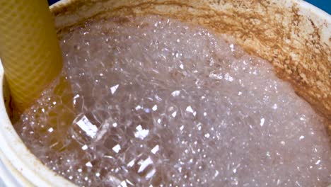 white foaming bubbles staining the side of a container as the yeast ferments the contents of the beer during the fermentation process.