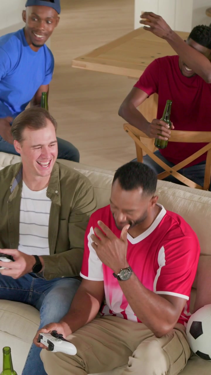 Vertical video: Holding pad gamer in jersey laughing while pal sharing phone home with soccer ball