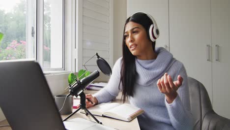 video de una mujer biracial con auriculares participando en una entrevista en línea en una computadora portátil en casa