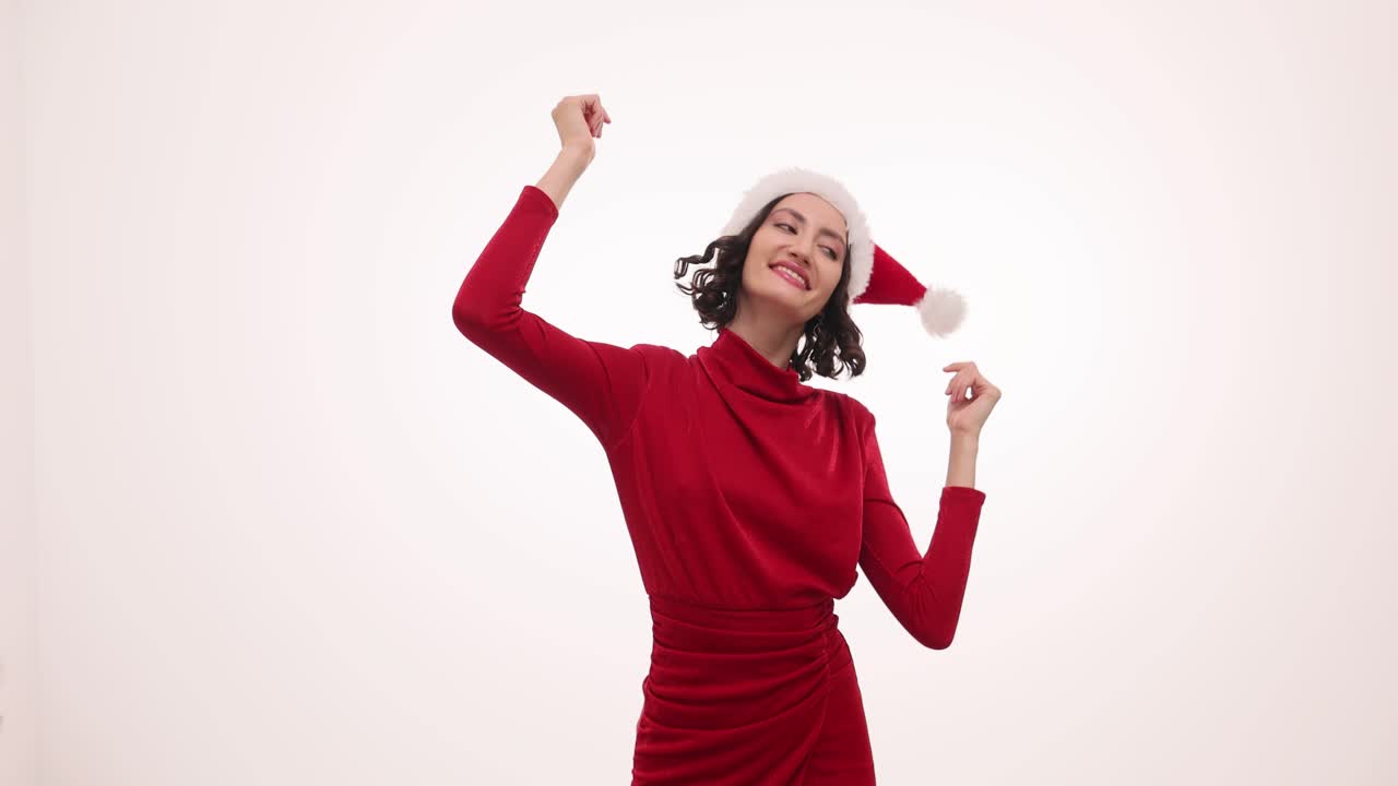 Joyful Woman in Santa Hat and Red Dress Dancing for Christmas