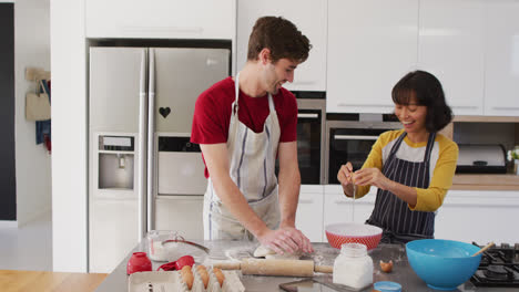 Video-of-happy-diverse-couple-baking-together-in-kitchen