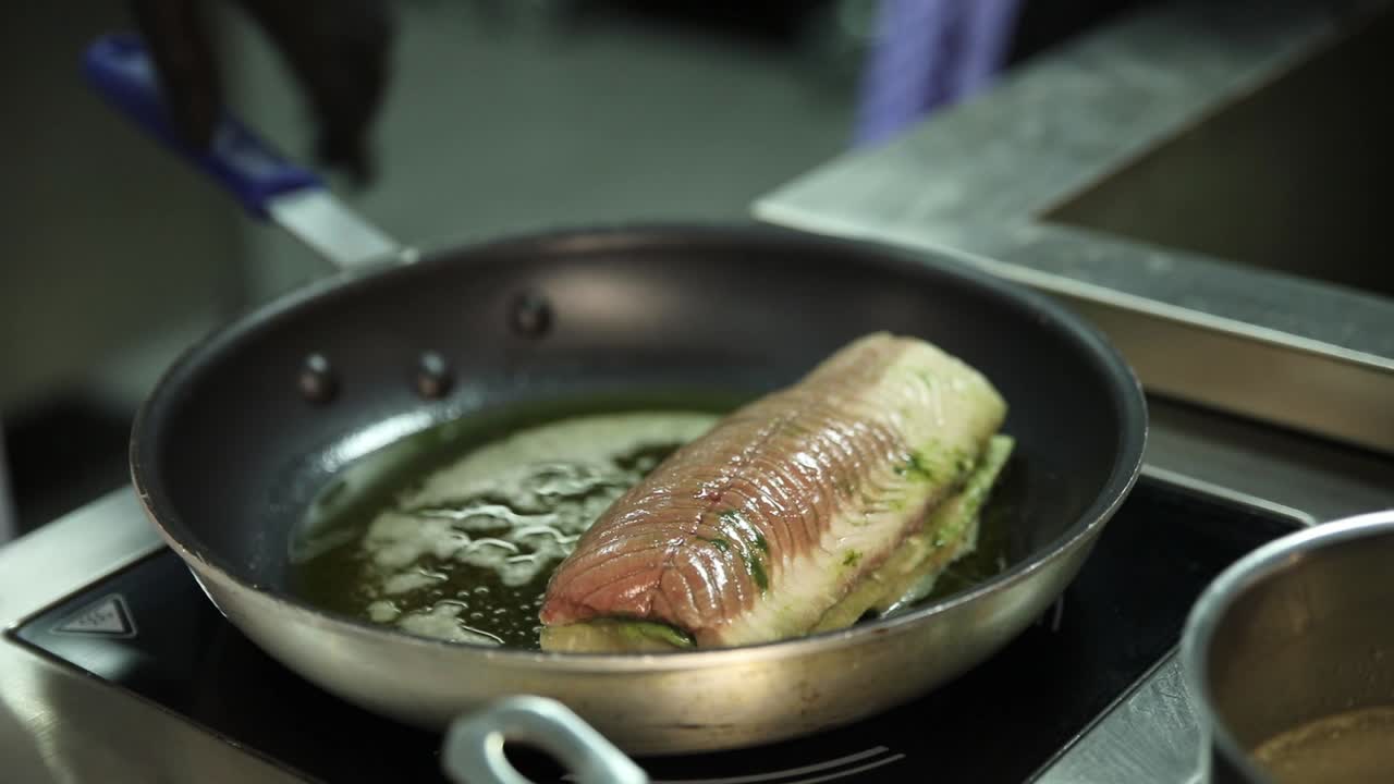 chef cocinando pescado en una sartén
