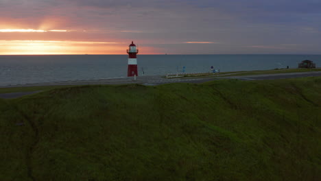 the lighthouse of westkapelle during a bright orange sunset, with a lot of wind