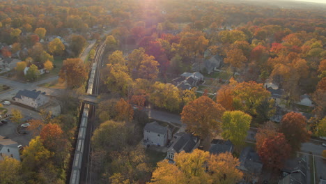 Aerial-following-a-freight-train-as-it-passes-by-a-train-station-in-Kirkwood-in-St