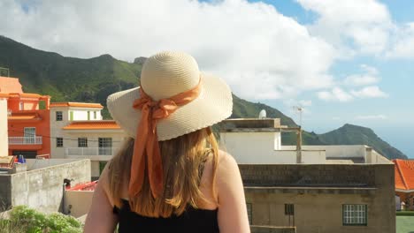 blonde white young woman with summer hat admires view outside resort in tenerife