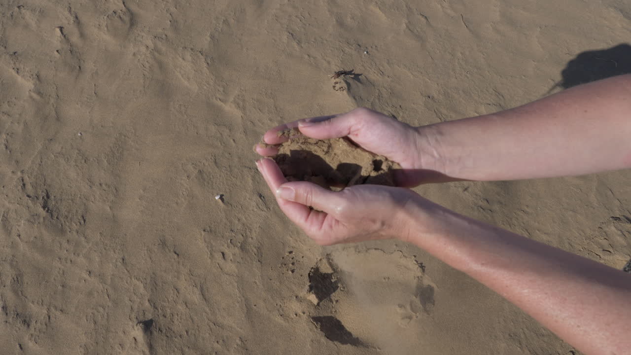 모로코에서 사하라 모래를 주워 손가락 사이로 미끄러지게 함