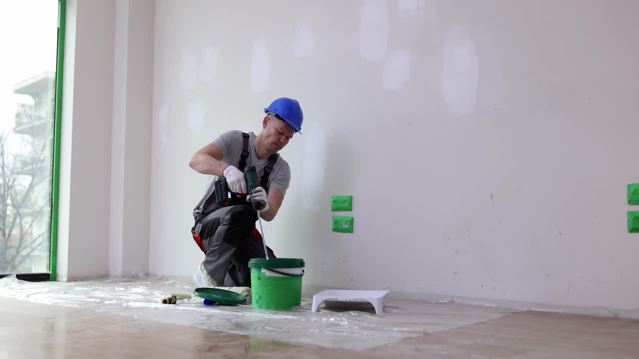 Construction Worker Mixing Paint with a Drill During Home Renovation