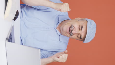 Vertical-video-of-Old-man-looking-at-laptop-applauding.