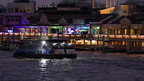 boat travels past illuminated riverside buildings