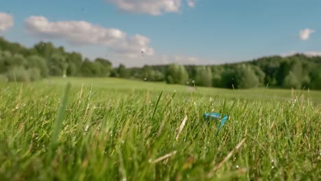 el palo de golf golpea una pelota de golf en una cámara súper lenta. gotas de rocío matutino y partículas de hierba se levantan en el aire después del impacto.