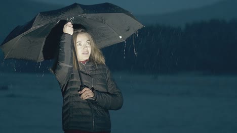 chica feliz posa con paraguas en cámara lenta por la noche