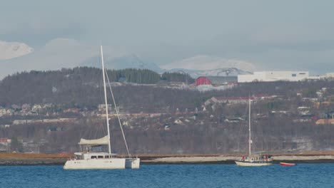 pequeño barco blanco navegando a lo largo del fiordo en tromso norte de noruega, teleobjetivo disparado en cámara lenta de 60 fps
