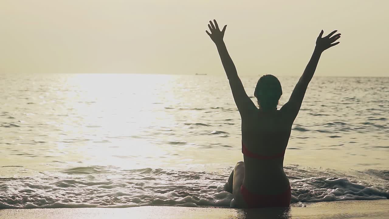 바다 가장자리에 손을 들고 있는 여성의 실루 ⁇  느린 동작