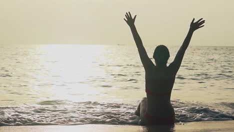 silhouette of woman raising hands on ocean edge slow motion