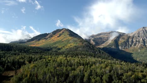 ascending aerial view of a mountain landscape with fall colors on the slopes