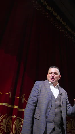 comedian rehearsing on scene. happy male actor performing in the theater dancing and singing on stage. orbital shot. vertical video