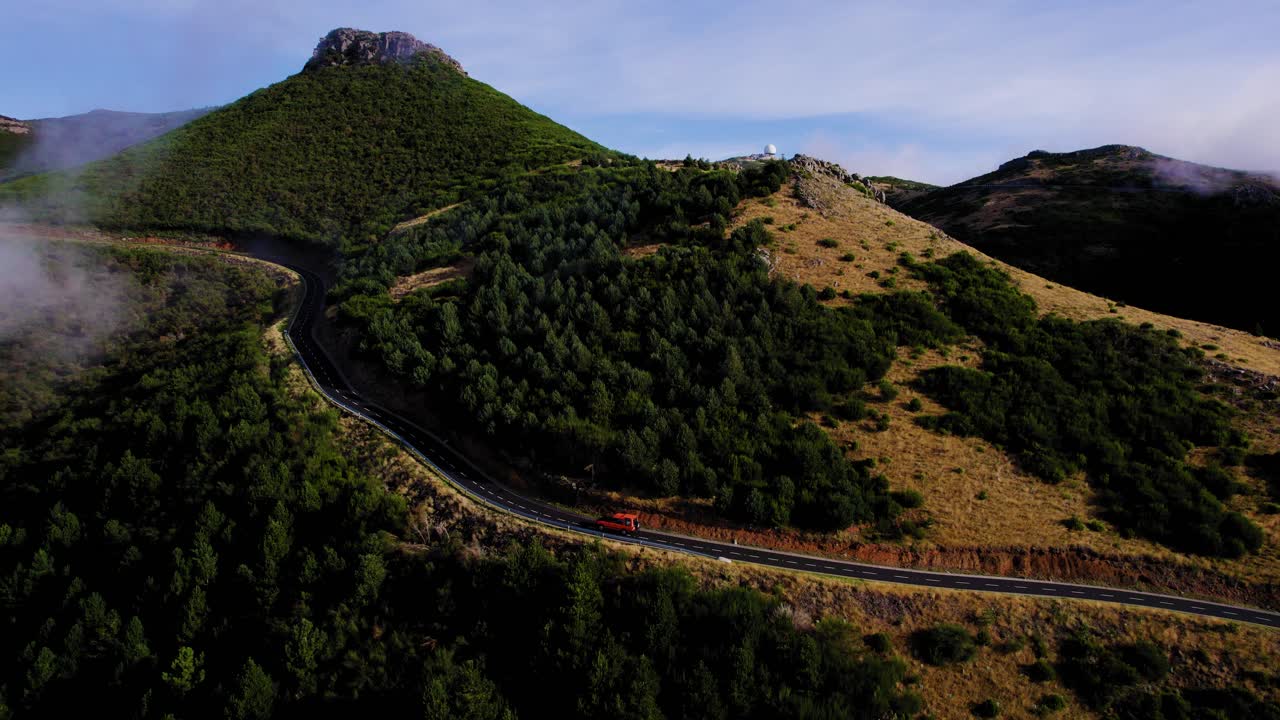 vista lateral aérea de un automóvil que conduce cuesta arriba en una carretera pavimentada