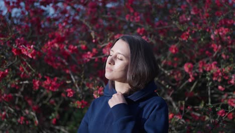 Thoughtful-caucasian-brunette-near-blooming-Chinese-Quince-shrub,-Prague