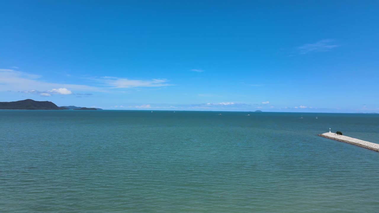 Serene Seascape: Calm Ocean with Blue Sky and Distant Mountains