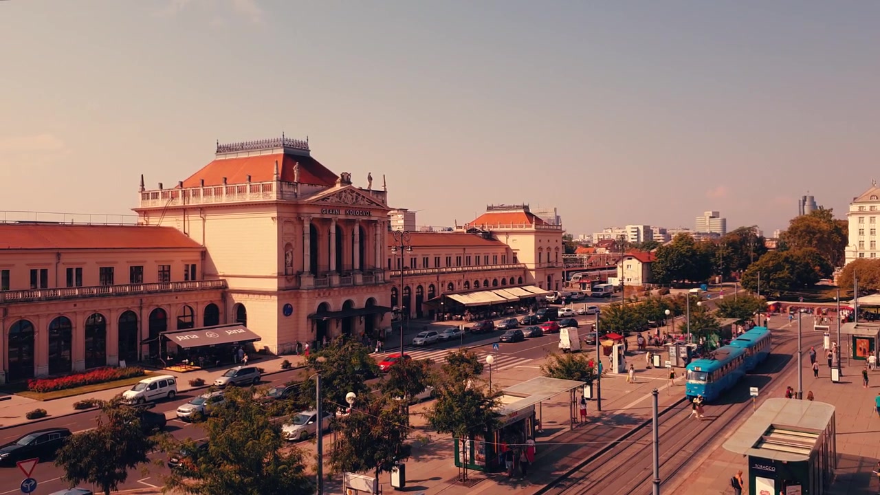 Timelapse in 4K che mostra persone, auto e tram in movimento su una piazza di fronte alla stazione ferroviaria