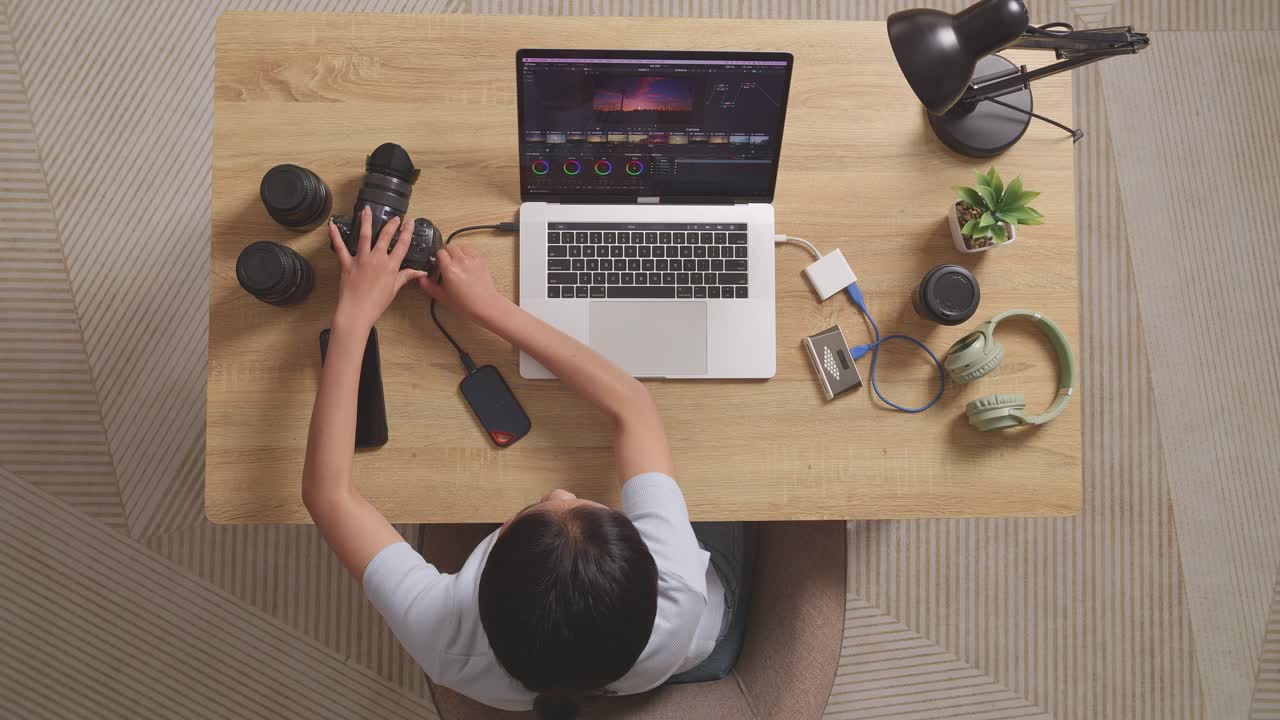 Top View Of A Woman Color Grading Putting The Memory Card On A Laptop Then Choosing The Video In The Workspace At Home