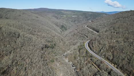 Navea-river-winds-below-mountain-pass-road-with-leafless-native-forest-of-oaks-and-chestnut-trees