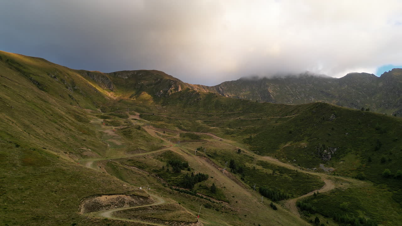 RIPRESA CON DRONE di una valle tra le montagne con una strada che sale verso le colline con un cielo nuvoloso