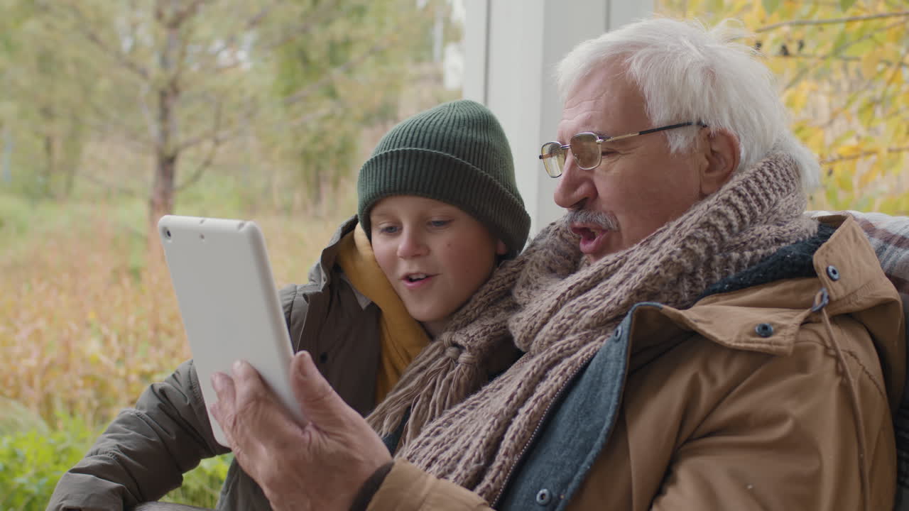 Grandfather and Grandson Using Tablet Together Outdoors