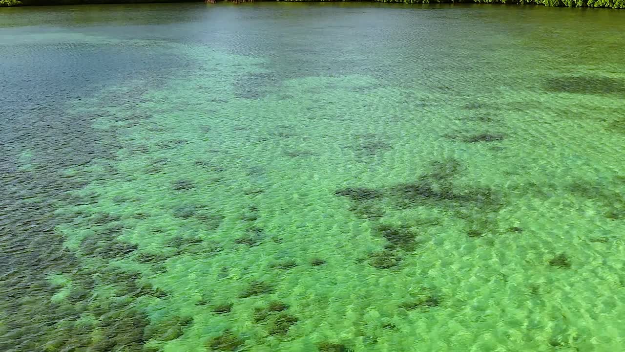 La telecamera drone si inclina verso l'alto dall'acqua turchese limpida per rivelare lussureggianti isole rocciose calcaree tropicali